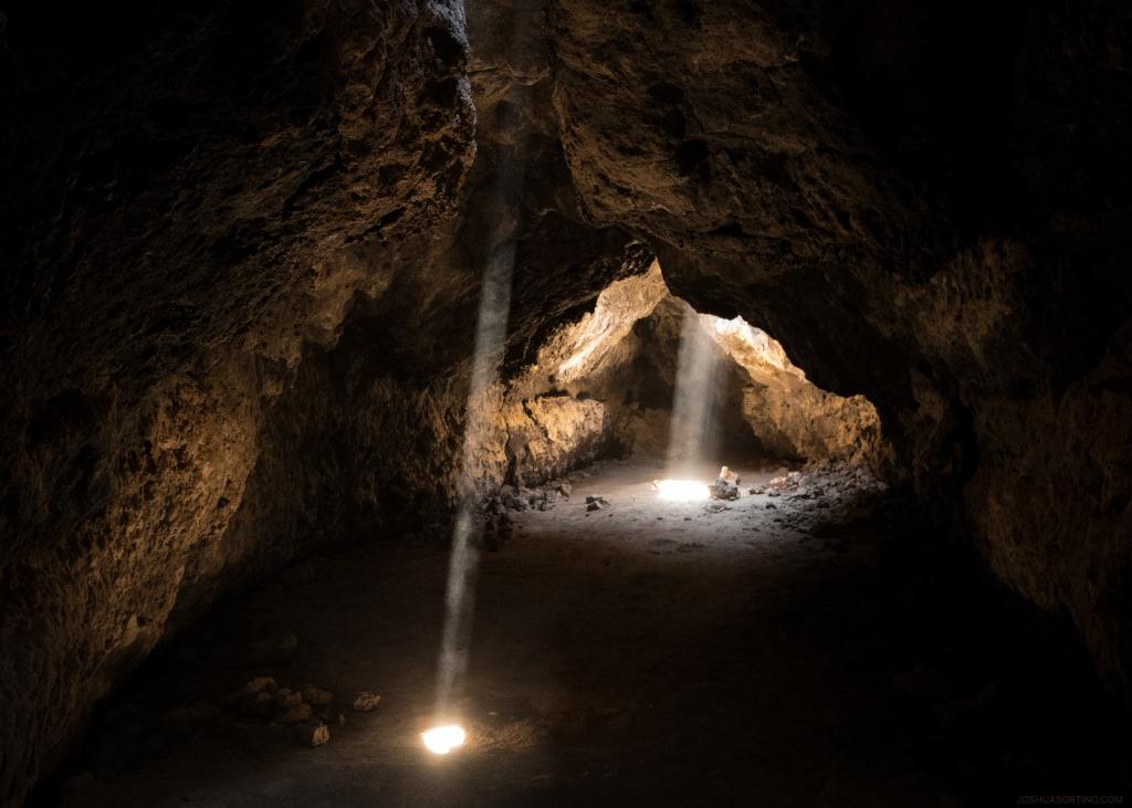 Bild einer Höhle in der Mojave Wüste deren Decke zweimal durchbrochen ist, wodurch das Licht herein fällt. Bild von Joshua Sortino/Unsplash